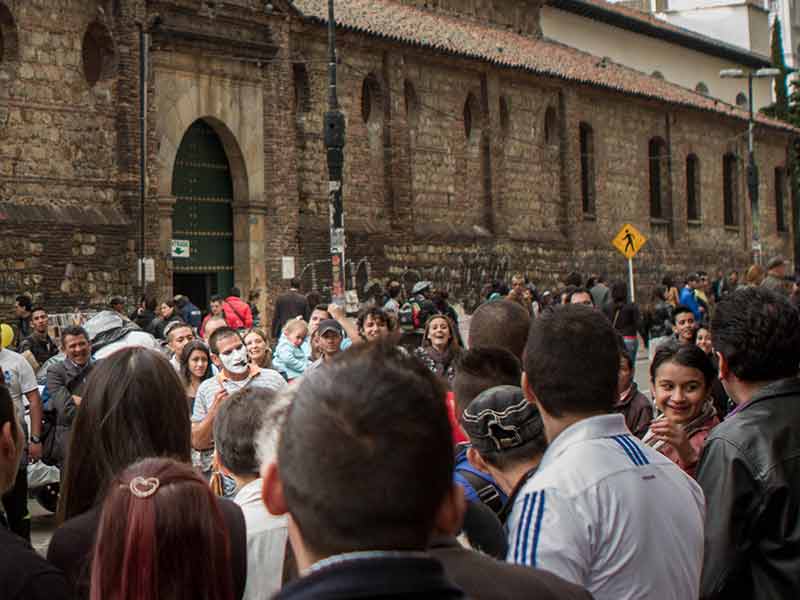 Crowd watches street performers on the streets just outside some of the oldest churches in Bogota.