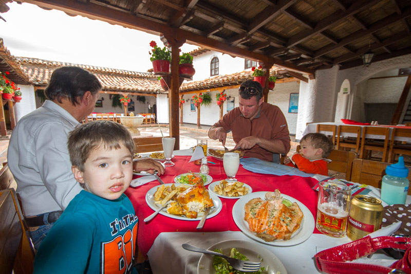 A young family eats lunch in an open air spanish style building - Legend of El Dorado in Colombia