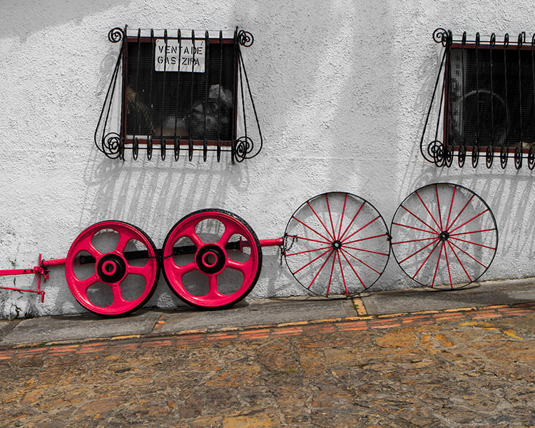 Old colourful tire rims lean up agains a white adobe style wall - Legend of El Dorado in Colombia