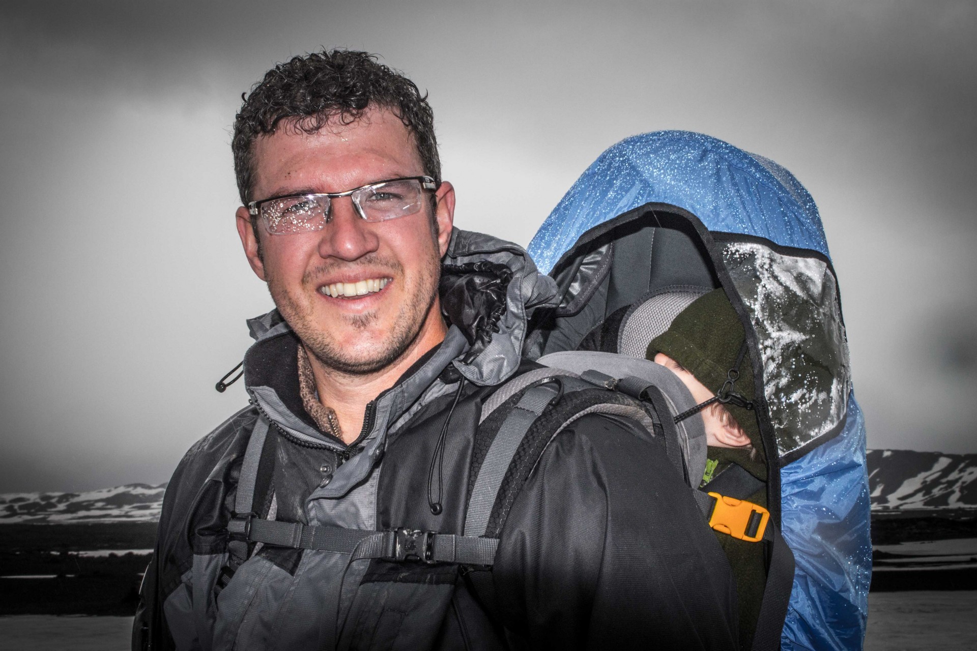 Man walks on a glacier while carrying an infant in a kid carrier - helping kids find nap time on the road