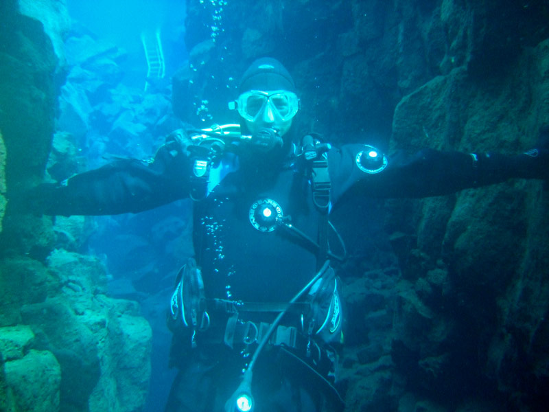 A SCUBA diver looks at the camera while touching the walls of two tectonic plates in Silfra Iceland in Thingvellir National Park