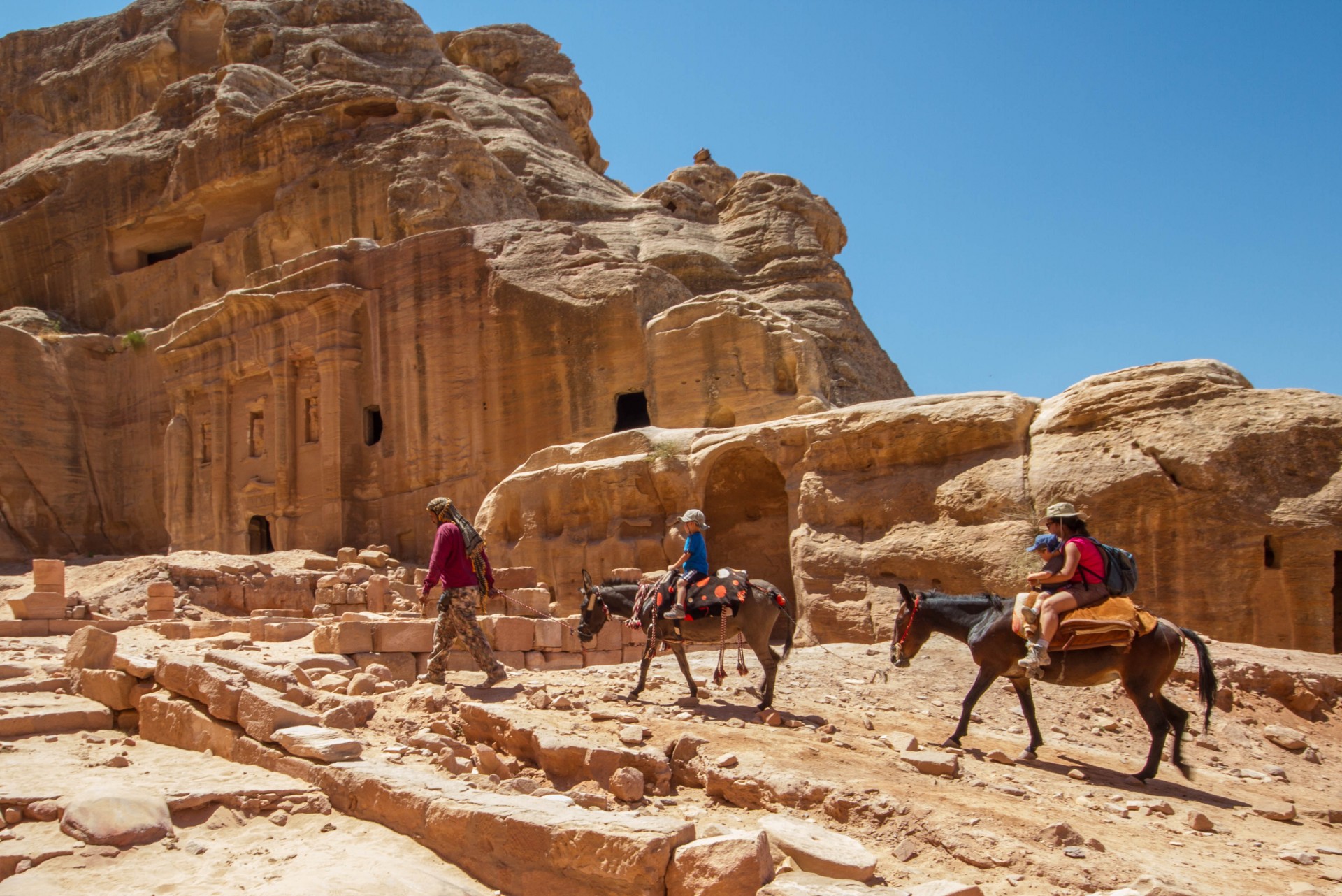 Family rides horses through Petra