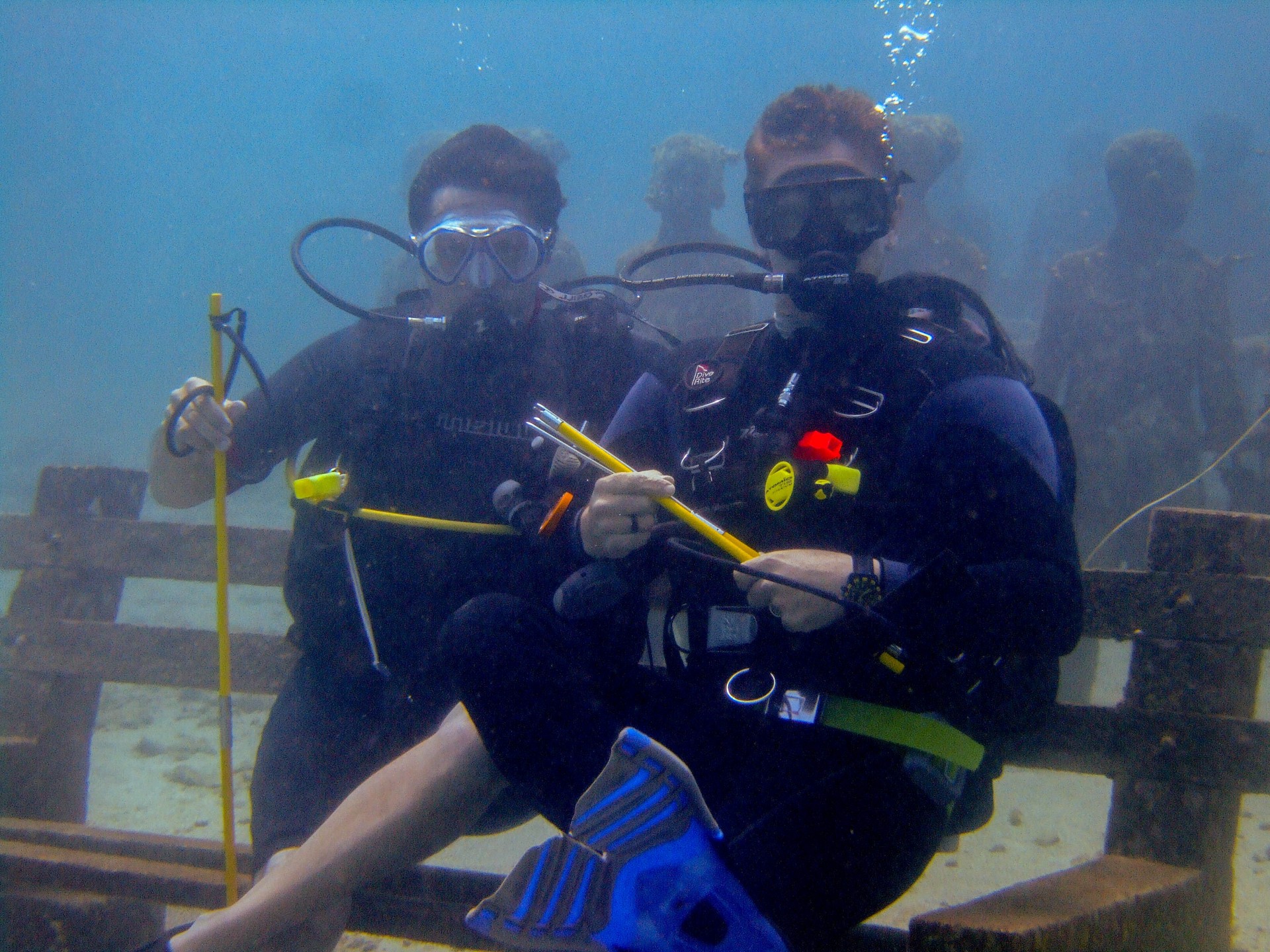 Divers sit on a bench at the Grenada underwater sculpture park