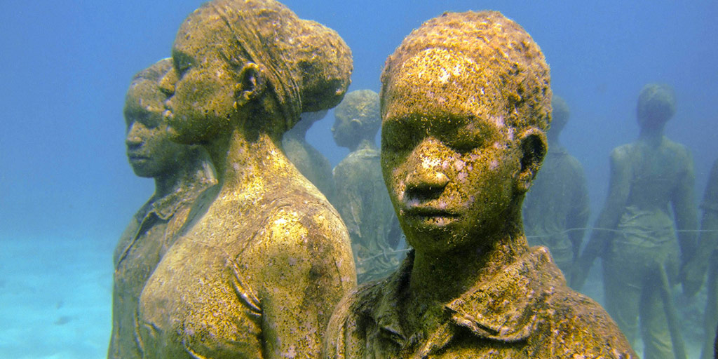 Statues of children holding hands in a circle beneath the ocean