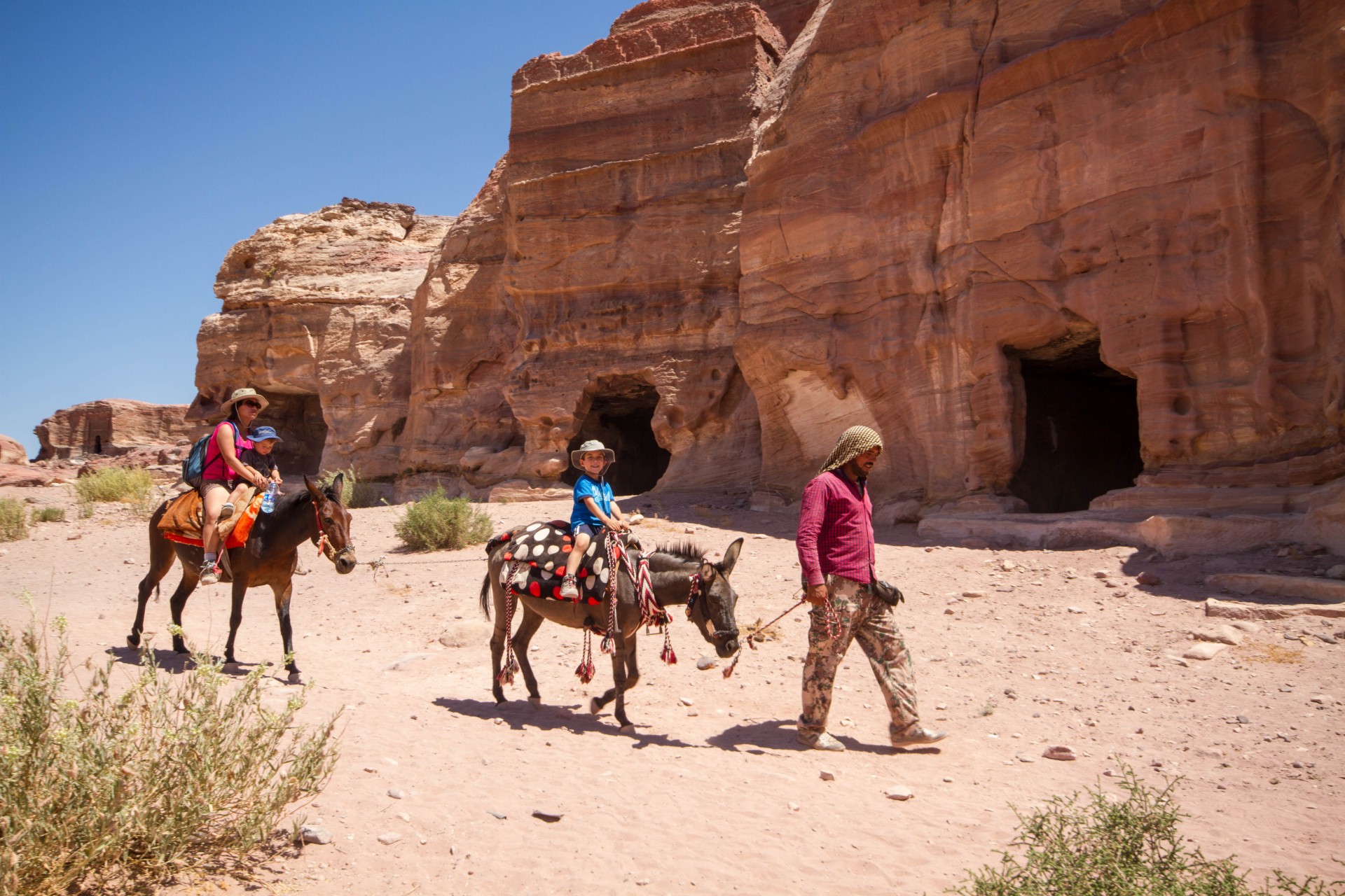 A family rides horses guided by a local in Petra