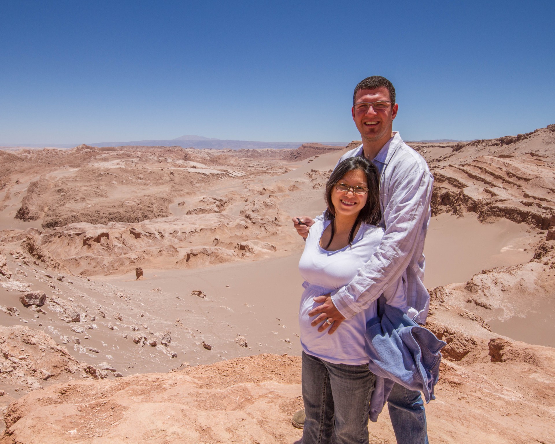 Man and pregnant wife pose for a photo at the Valley of the Dead in Chile