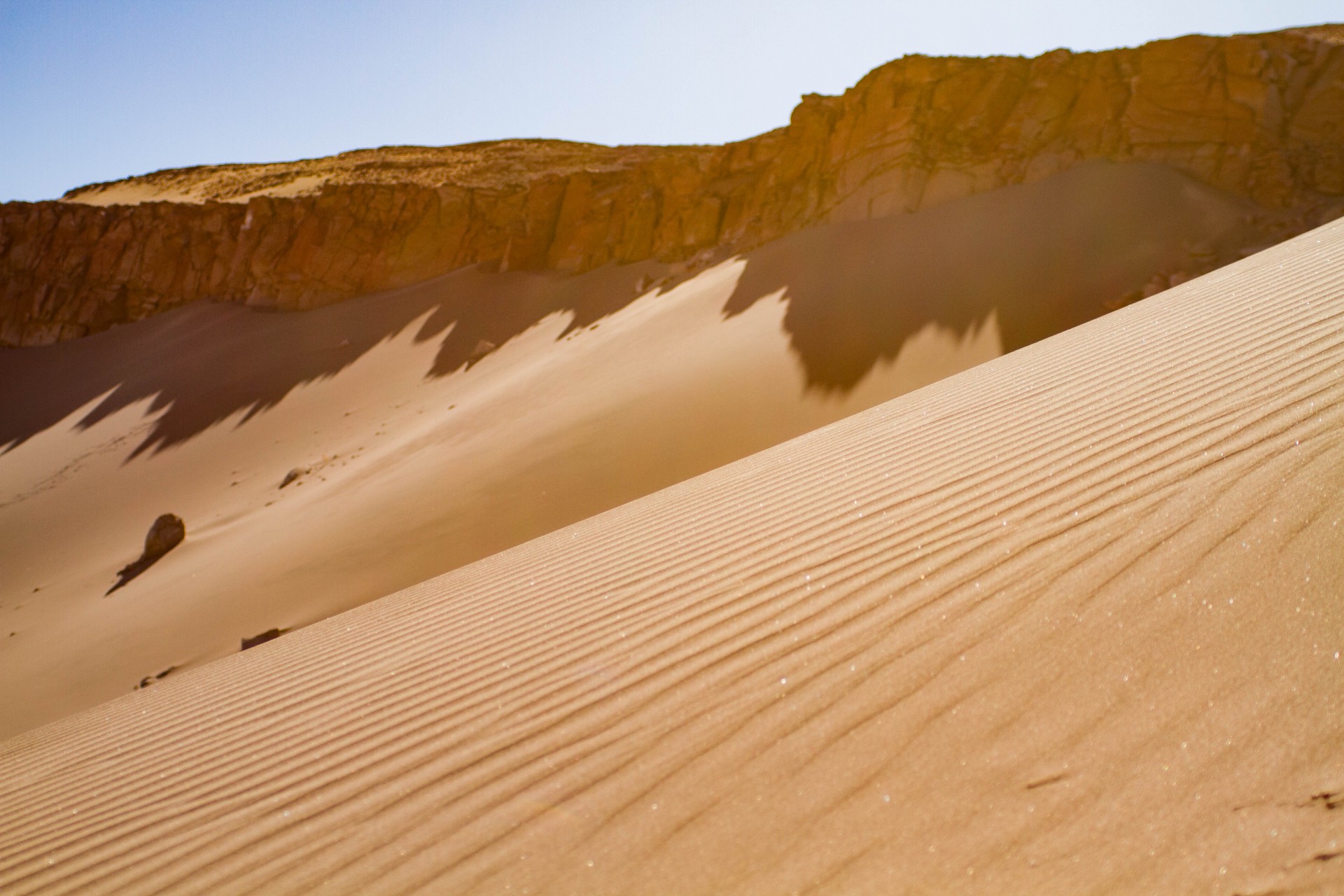 Sand dunes are built up again a rocky ledge in the Atacama desert