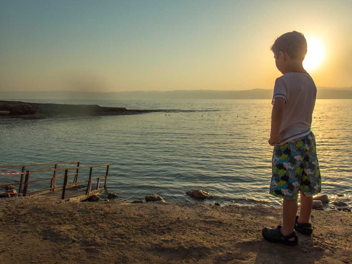 A young boy stares out at the waters of the Dead Sea in Jordan