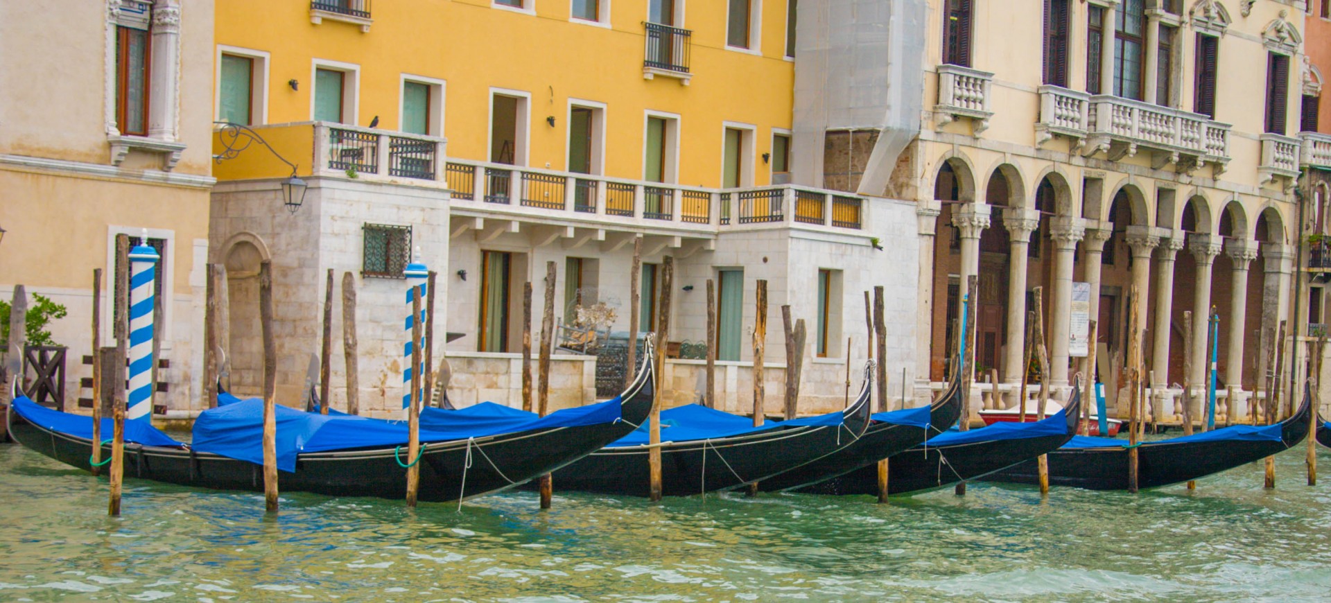 Gondolas parked in a line next to colourful buildings in Venice, Italy - Lost in Venice