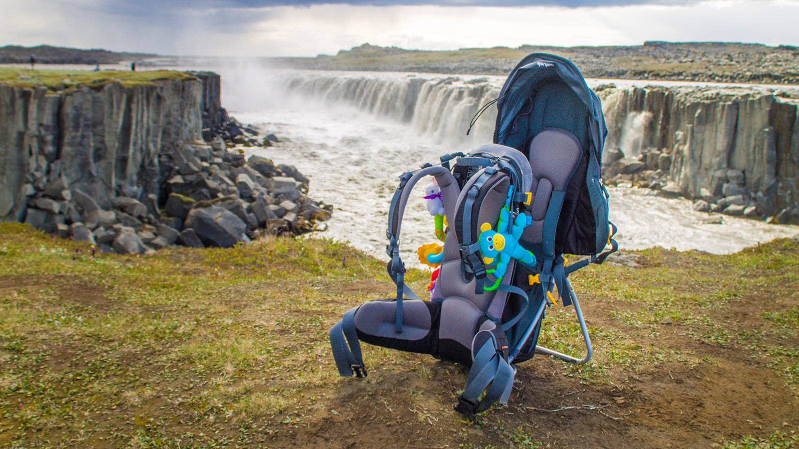 Kid carrier Deuter Kid Comfort III on grass at the top of of a cliff in front of waterfalls