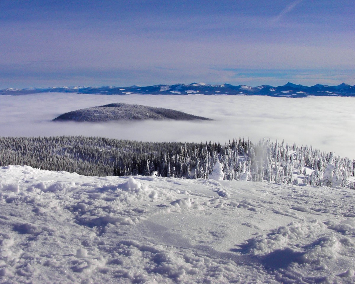 A mountain top peaks out above the clouds - Learning to ski at Kelowna's Big White