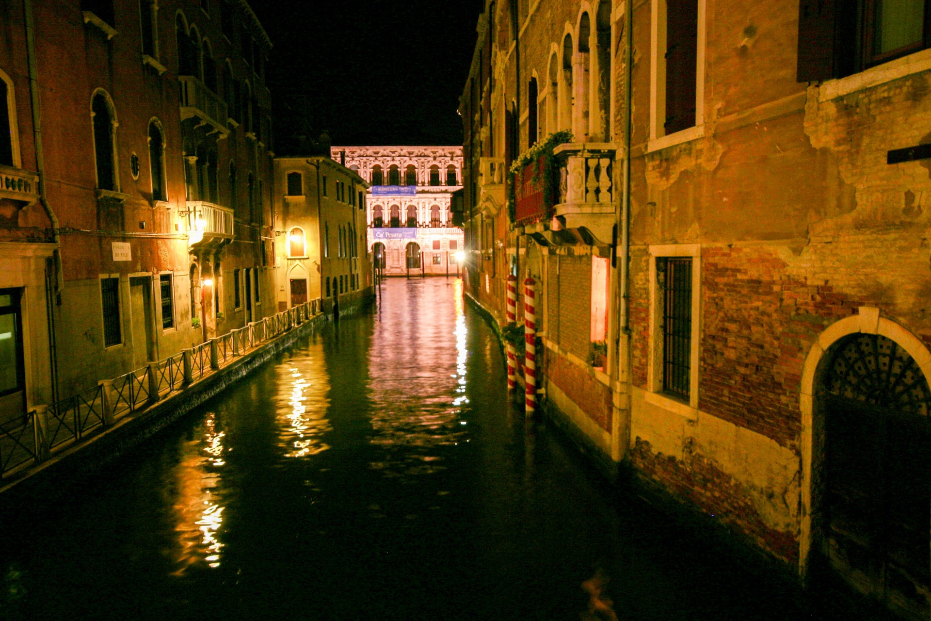 A river in Venice Italy at night is dotted with reflections of light from the surrounding buildings - Lost in Venice