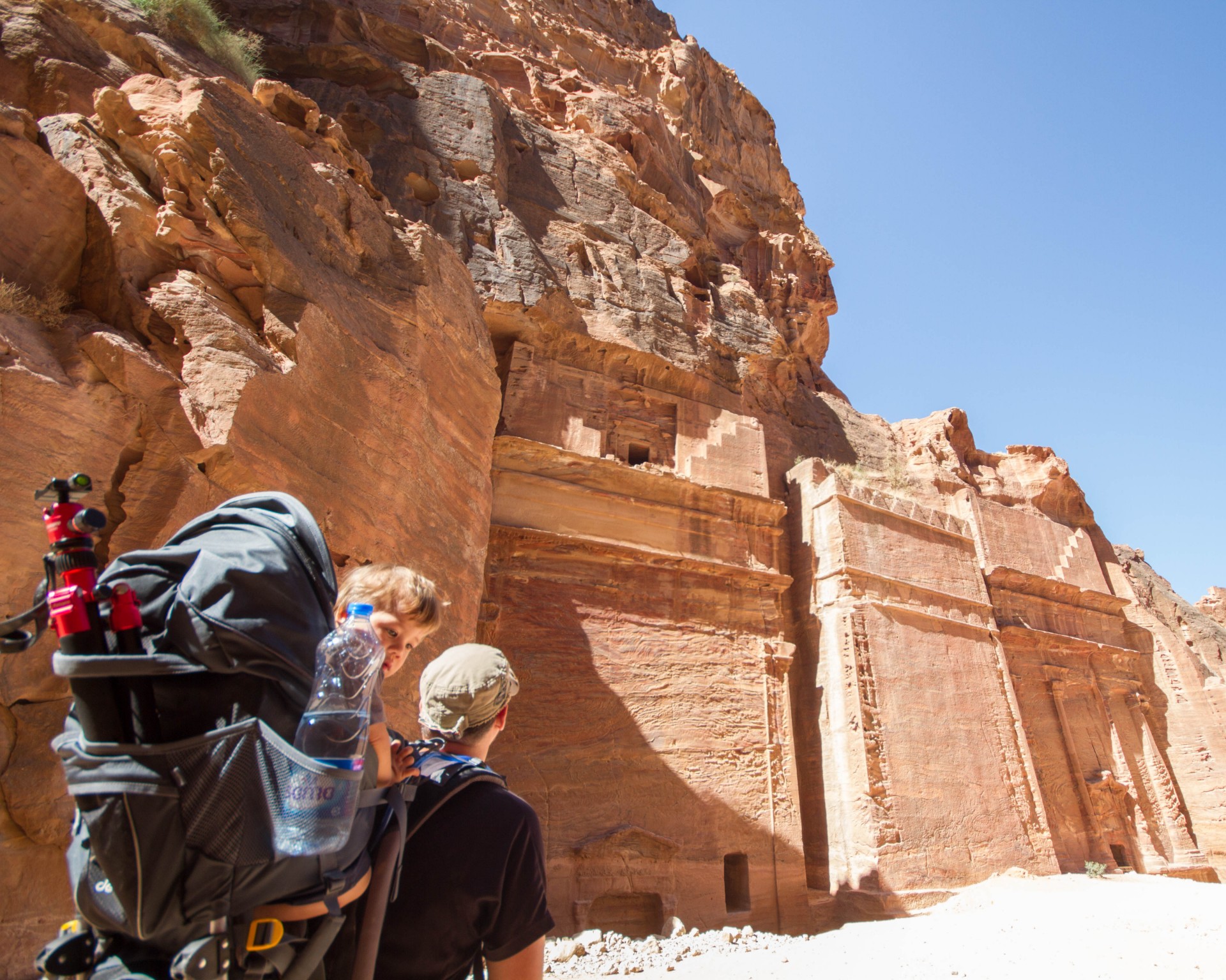 Child looks at the camera from inside a Deuter Kid Comfort III Kid Carrier while his father hikes through Petra Jordan