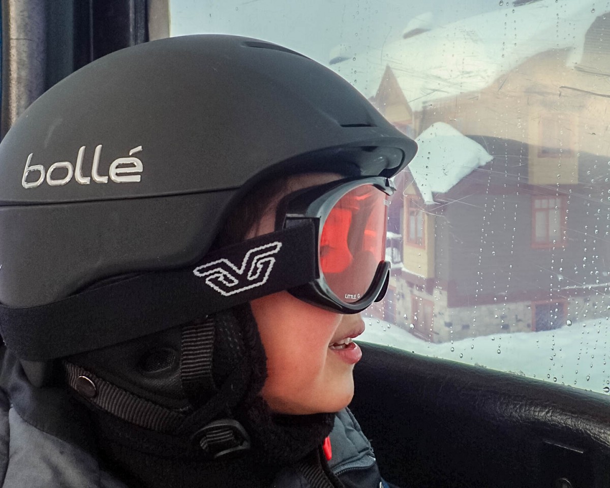 Young boy in ski helmet and goggles looks out from a window - Learning to Ski at Kelowna's Big White