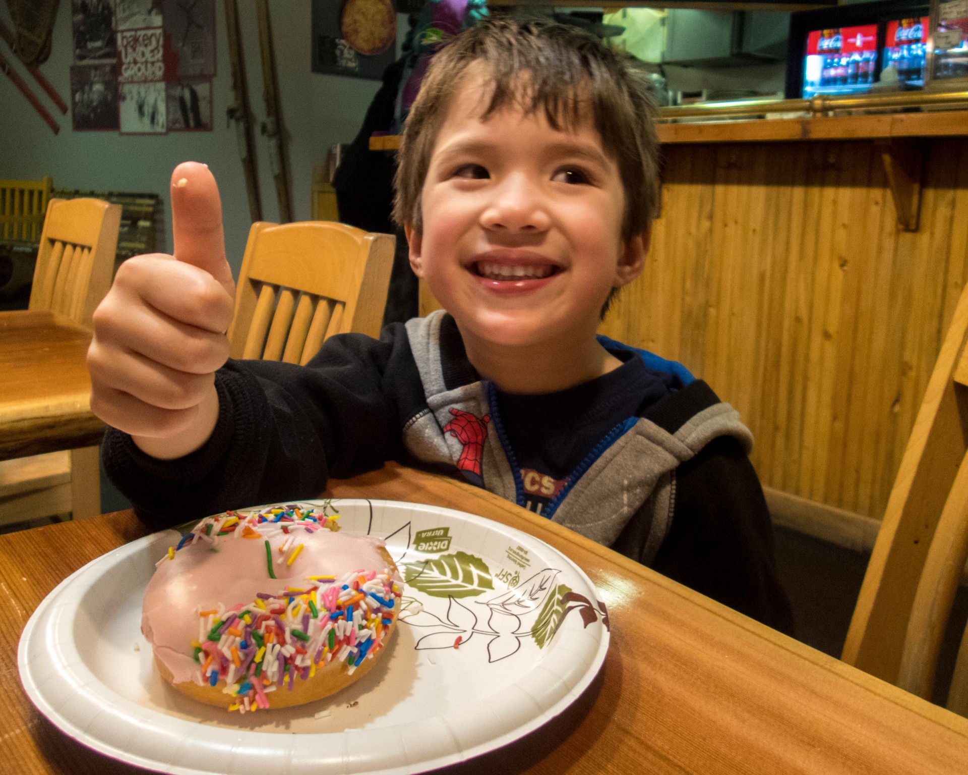 Young boy eating a donut gives a thumbs up - Learning to ski at Kelowna's Big White