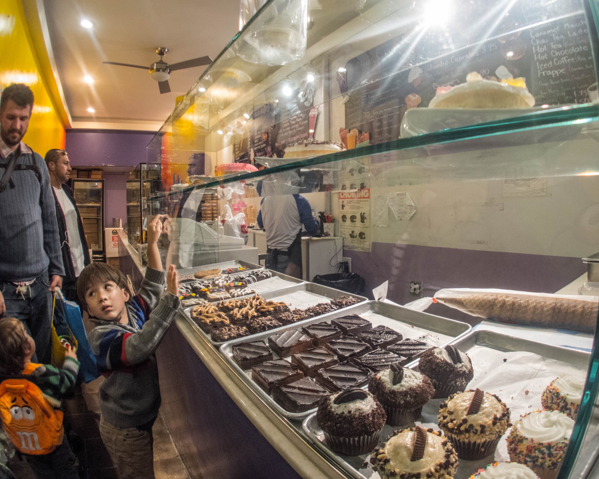 A young boy points at treats in a bakery window