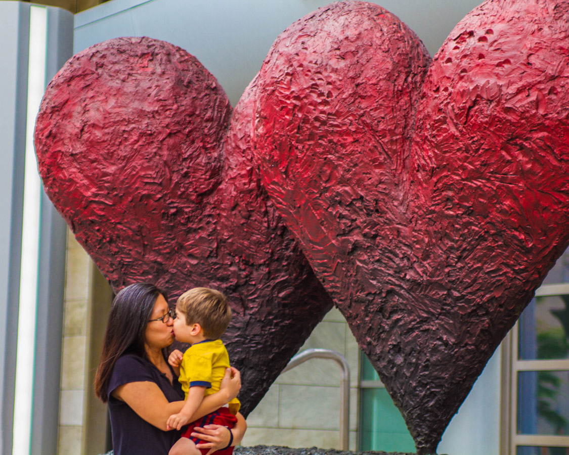 A mother and son share a kiss near heart sculptures in Quebec City on a road trip to Perce Quebec and Bonaventure Island