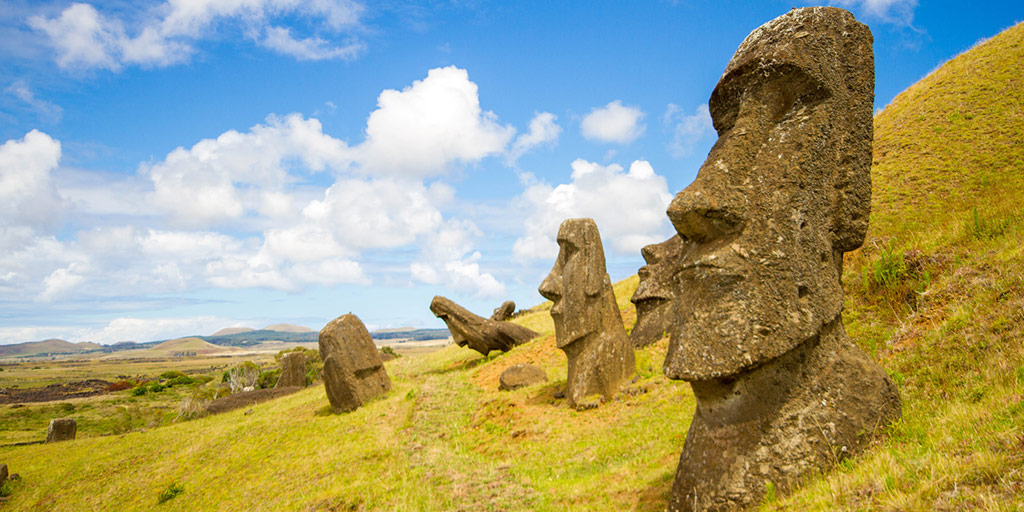 A moai sculpture sits partially buried in green grass on Easter Island