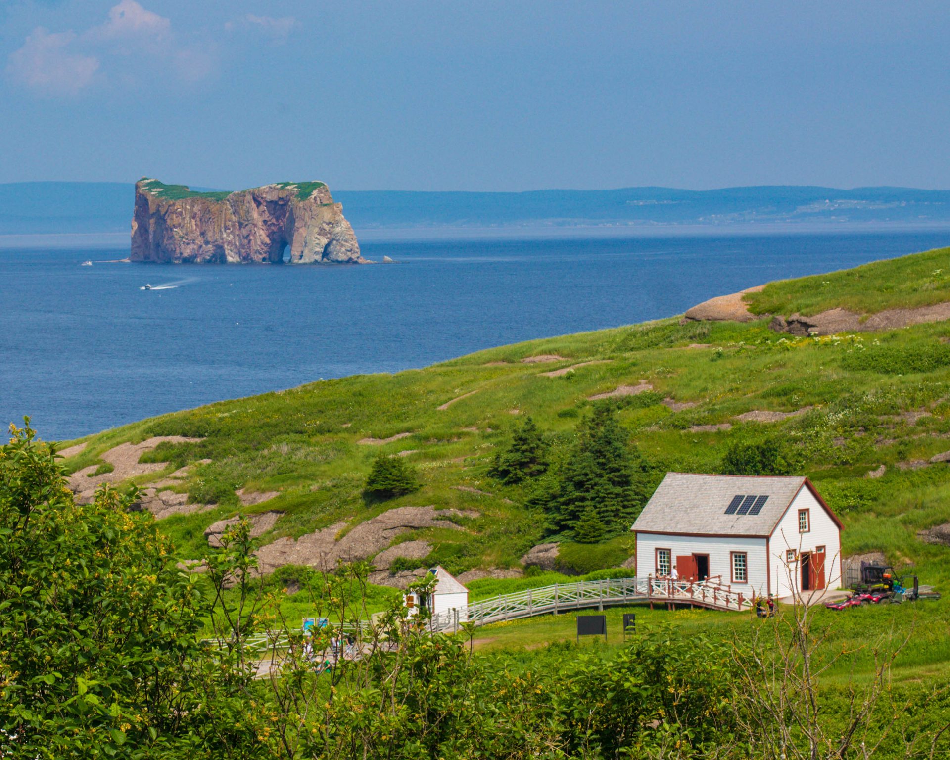 A colorful farmhouse on Bonaventure Island and Perce rock in the distance