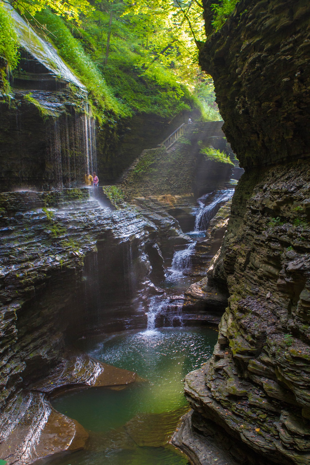 Glen of Pools with rays of sun streaming down onto the gorge and rock bridge in the background.