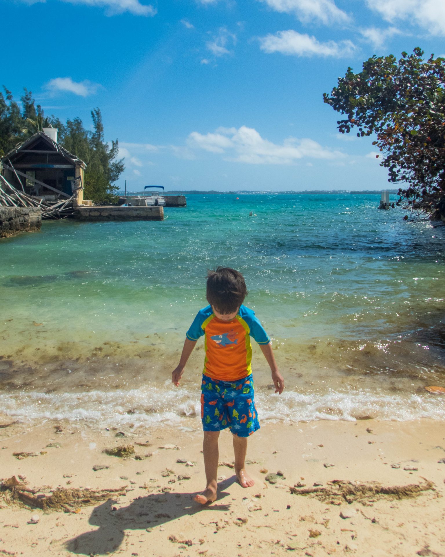 A young boy in swim gear walks out of the waves of a small cove in Bermuda - Boating in Bermuda