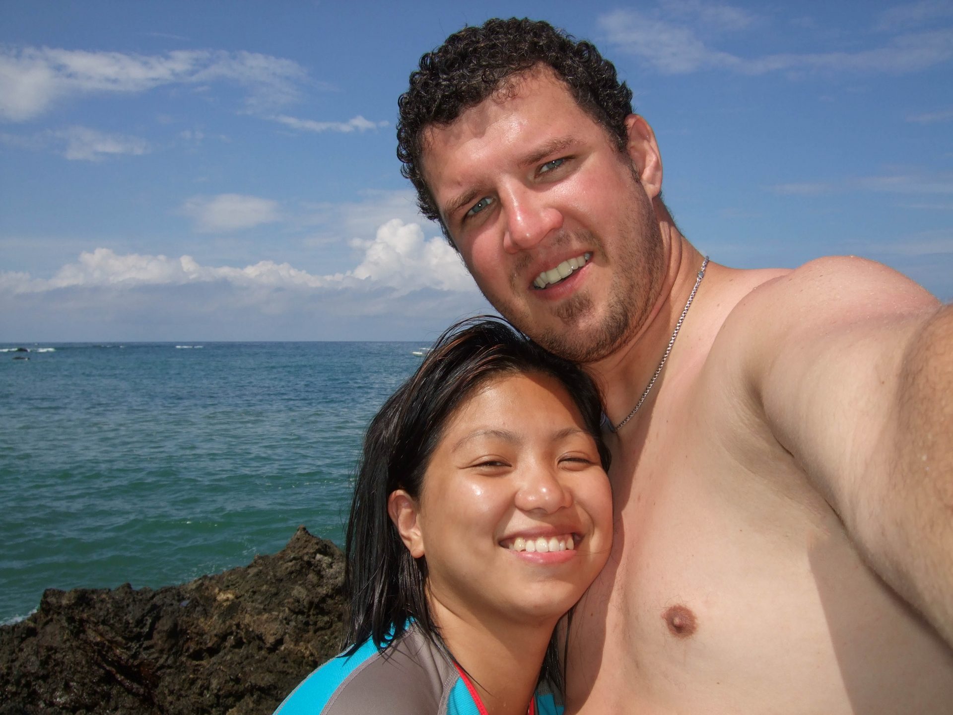 A young man and woman hug and smile at the camera - finding paradise in the osa peninsula