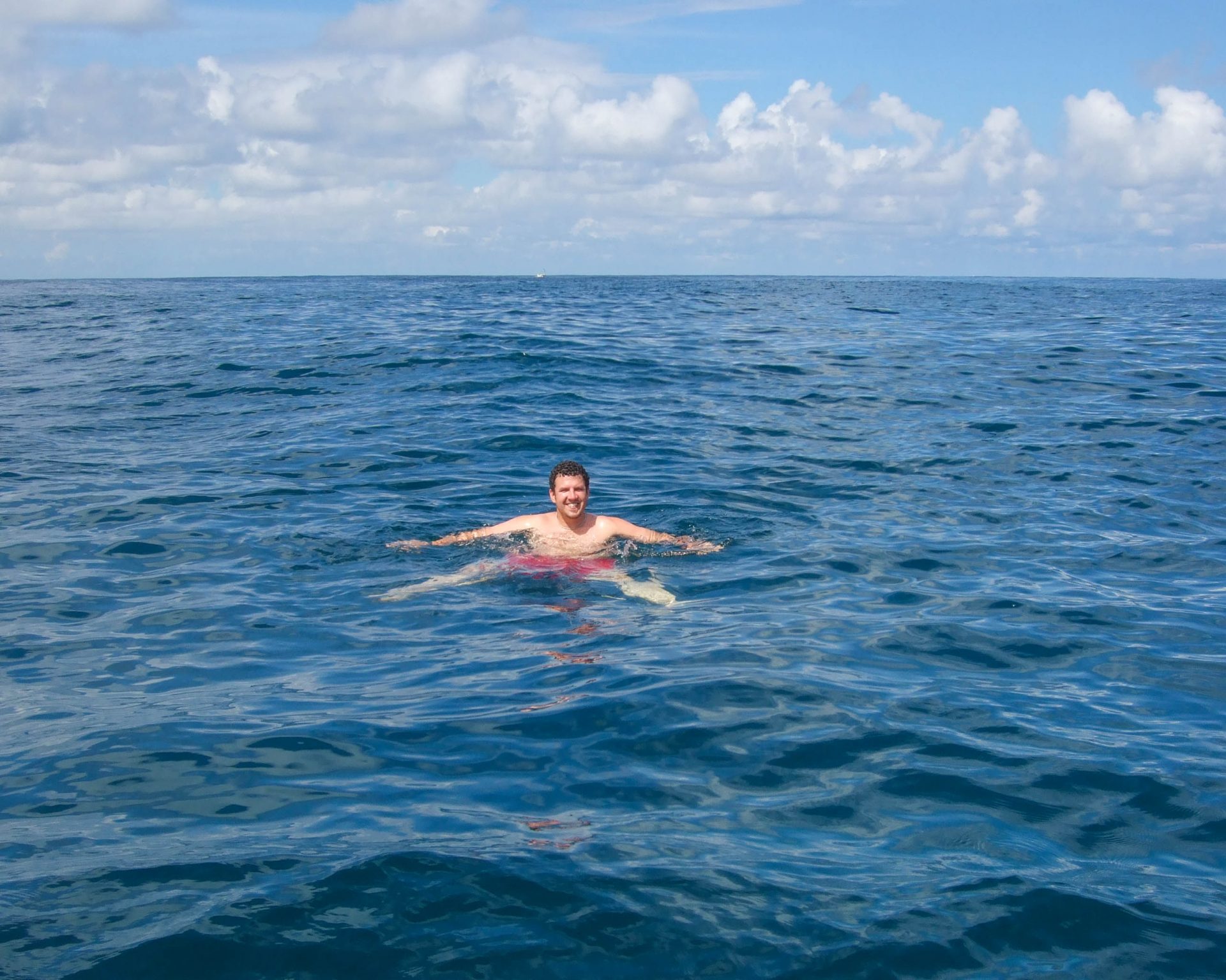 A man smiles while swimming in the middle of the Caribbean sea - finding paradise in the osa peninsula