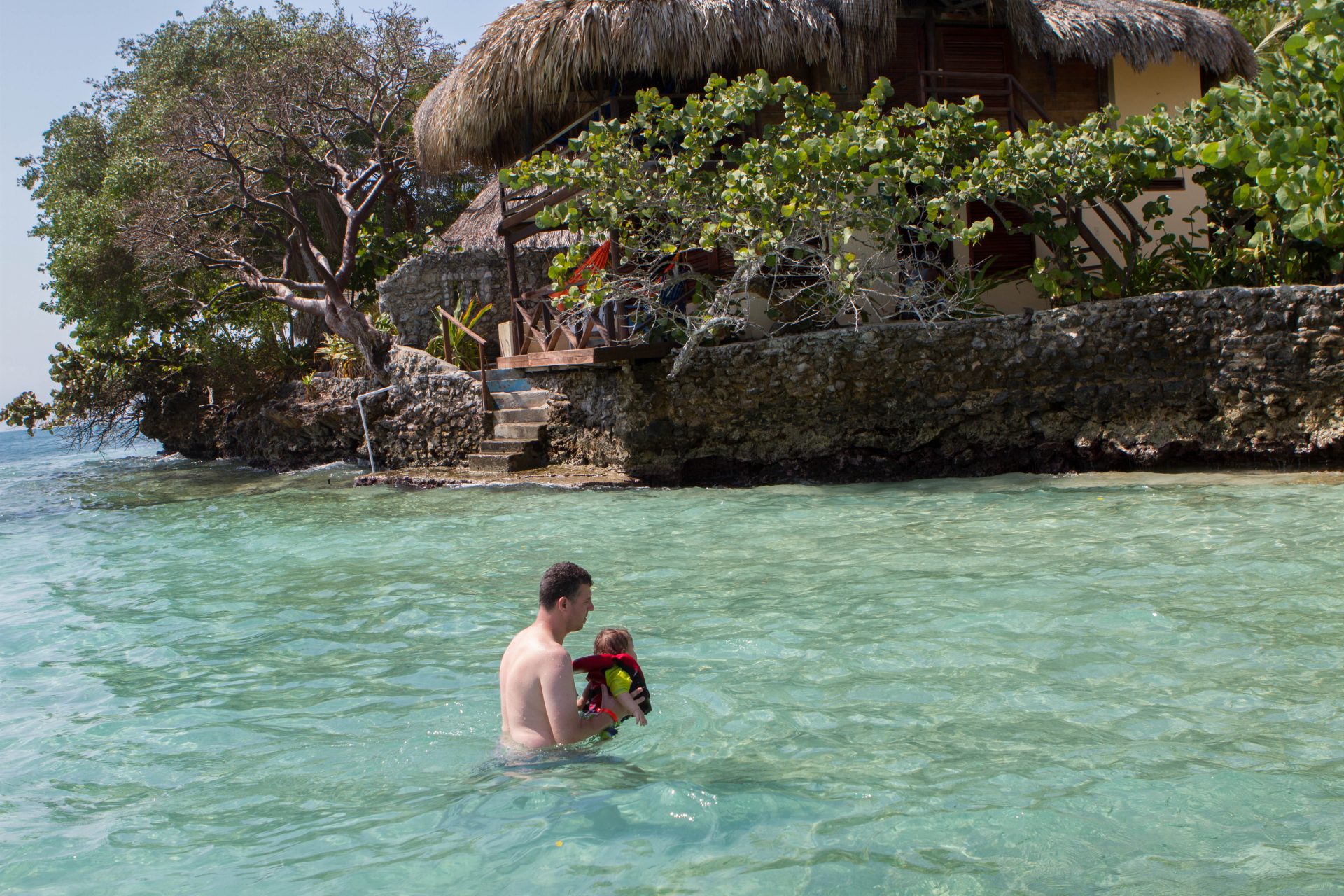 Man holds baby in the waters off of Pirate Island.