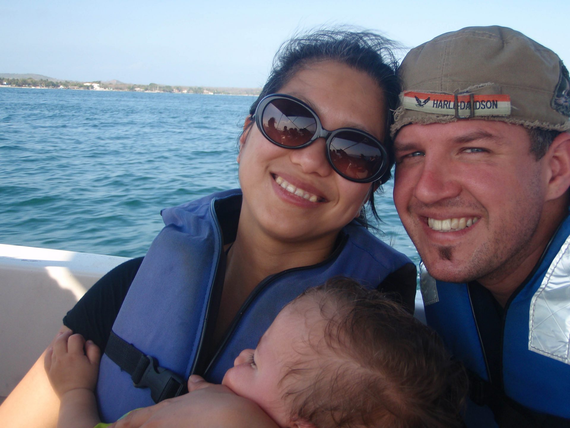 Mom holding her son with father beside her while on a boat to Pirate Island.