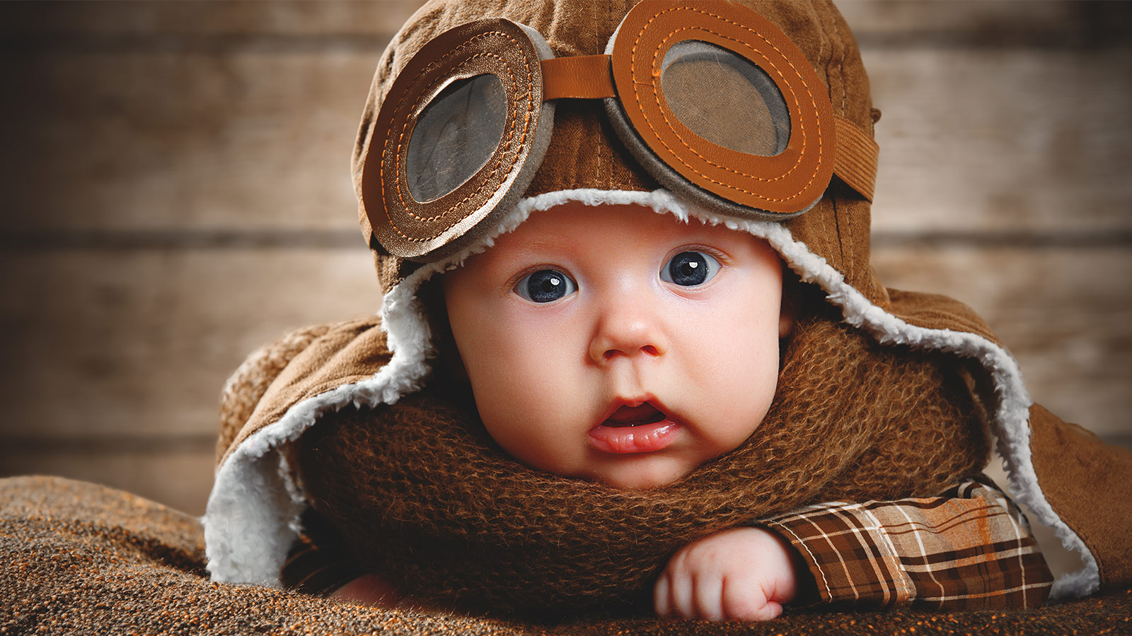 Baby in a vintage pilots outfit looking at the camera - Flying with a baby