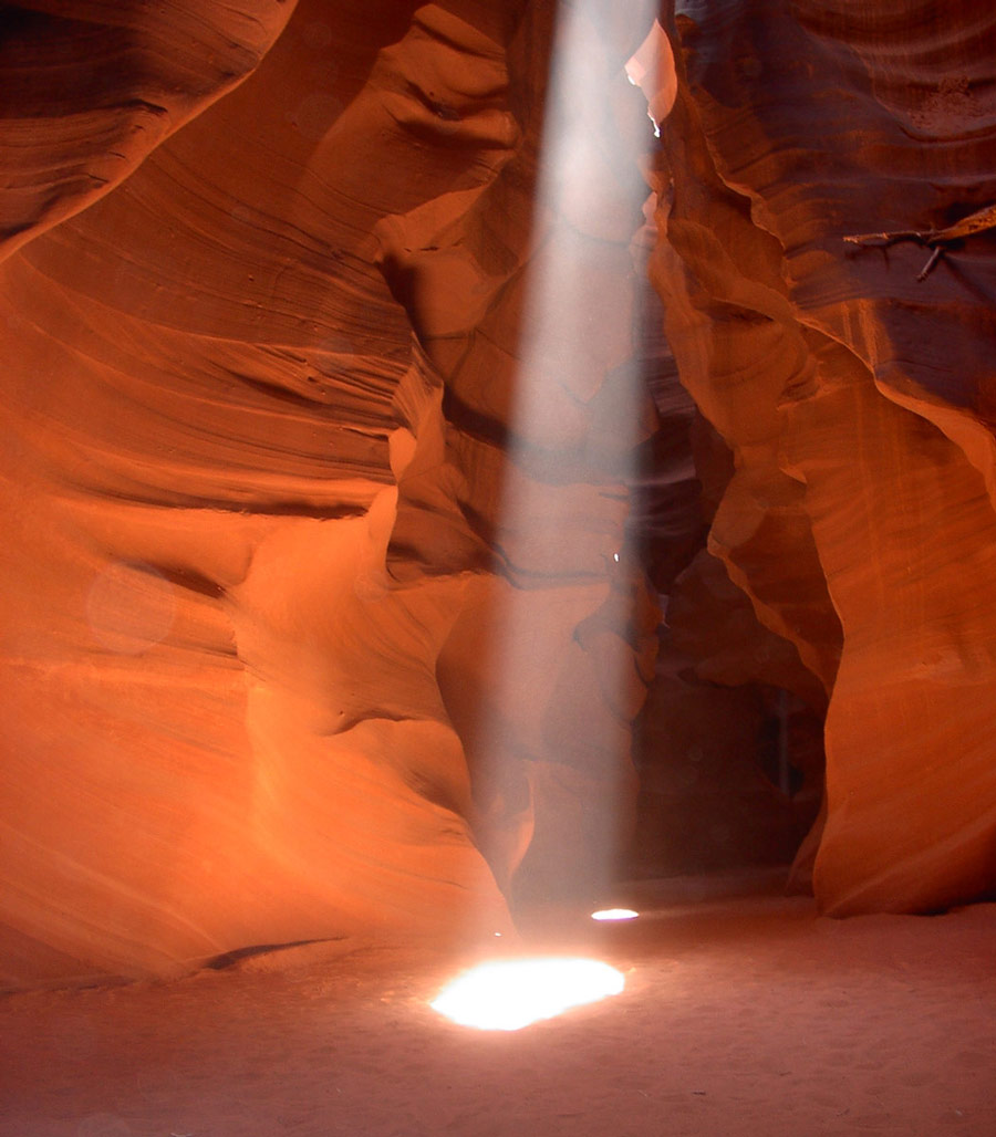 a shaft of light beams down over a the sandy bottom of a slot canyon - things to see in the American Southwest
