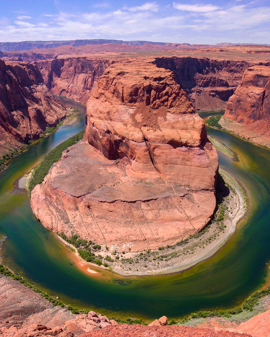 The green Colorado River bends around a tall red rock cliff in Utah - things to see in the American Southwest