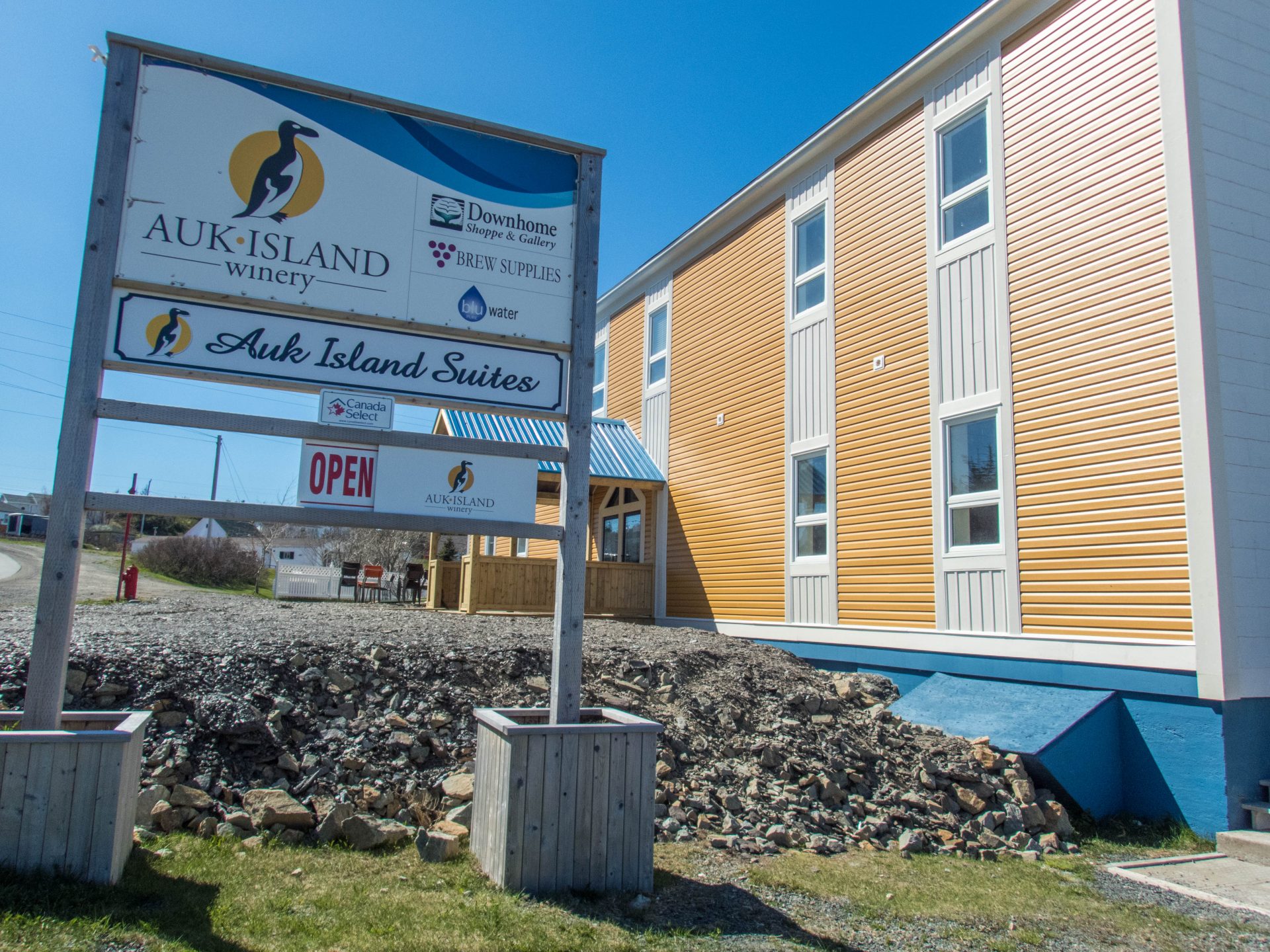 a sign for a winery sits in front of a yellow and white building - Icebergs in Twillingate
