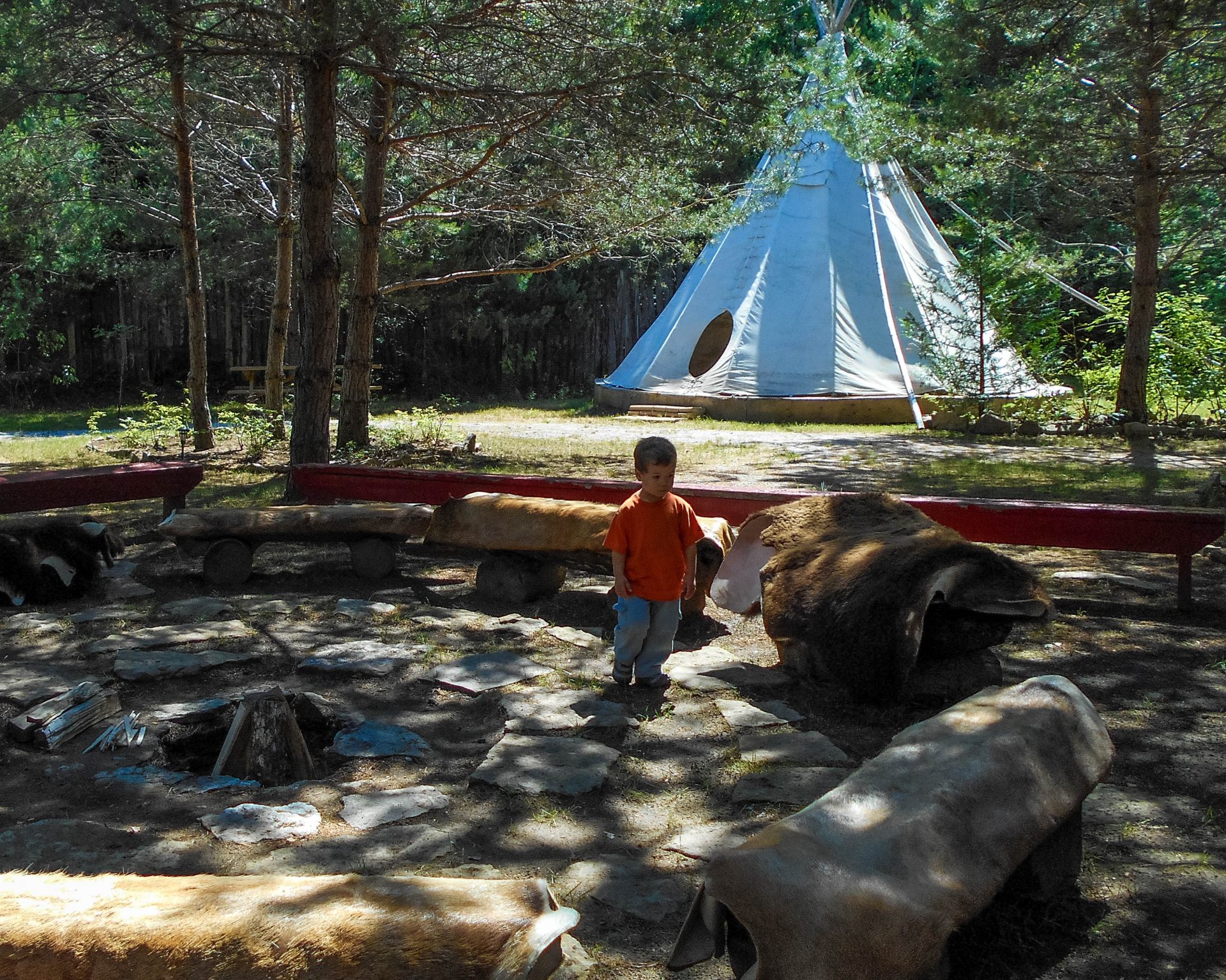 Young boy exploring the area around the firepit at the Great Spirit Circle Trail on Manitoulin Island.