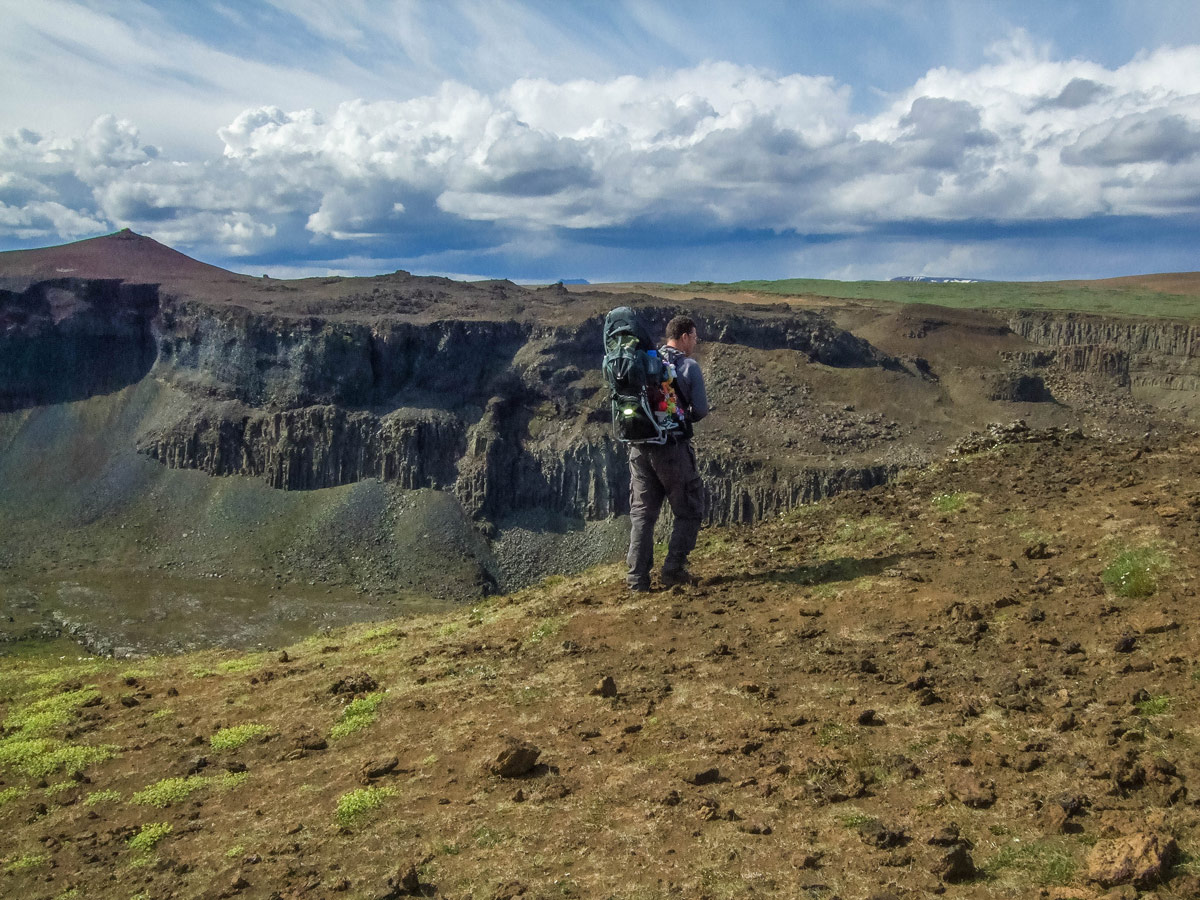 a man carrying a child in a kid-carrier hikes along a canyon rim - An Epic 14 Day Iceland Itinerary