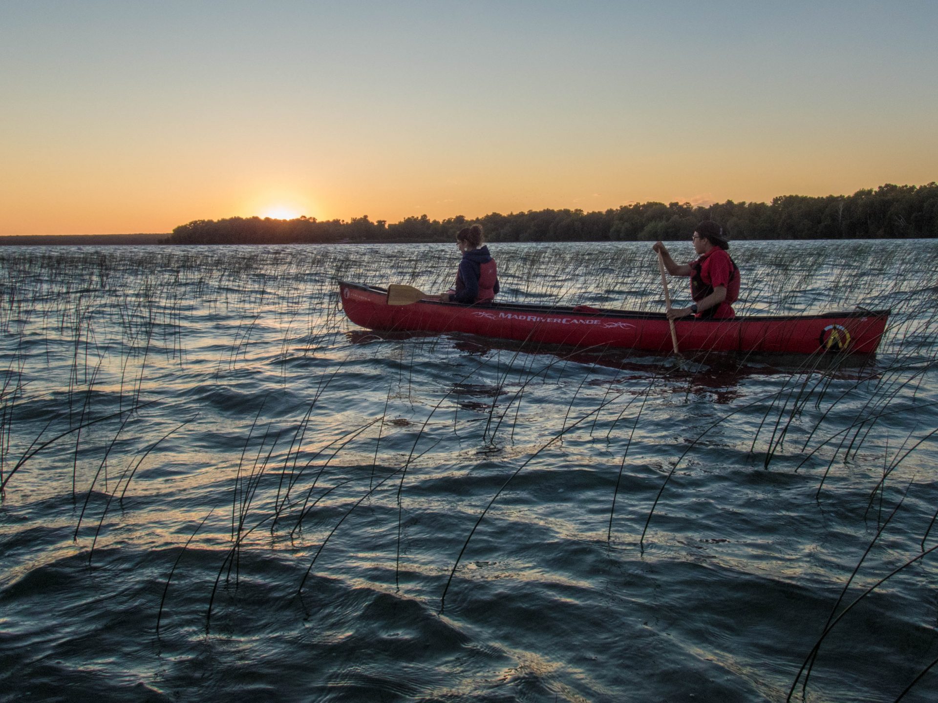 Two people on a canoe witness a gorgeous sunset on Lake Manitou as part of the Great Spirit Circle Trail Sunset Canoe Experience on Manitoulin Island.