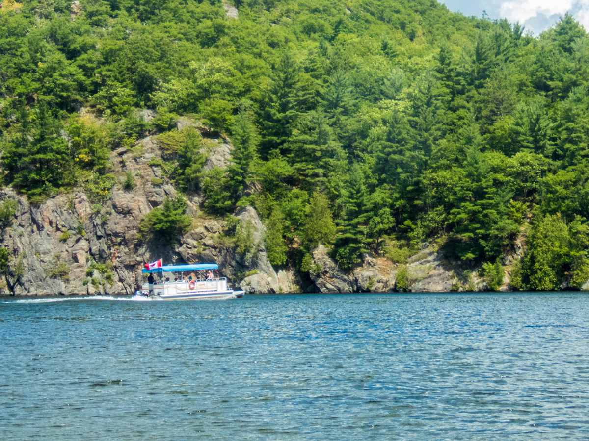 A tour boat drives along the steep cliffs of Bon Echo provincial park - Mazinaw Lake & Cliffs Tour Boat