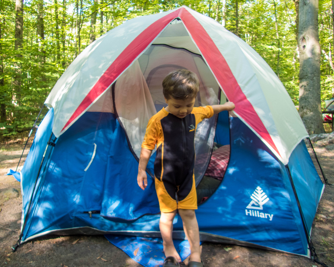 A young boy wearing a wetsuit climbs out of a tent - Top things to do in Bon Echo Provincial Park