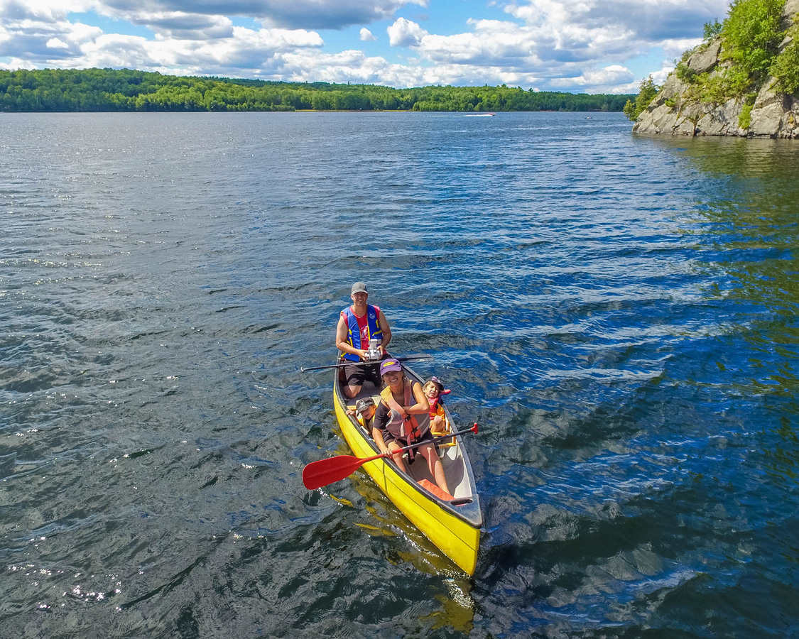 An aerial shot of a family canoeing across a lake - Top things to do in Bon Echo Provincial Park