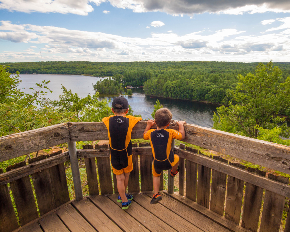 Two young boys wearing wet suits look over a railing at the lagoon in Bon Echo - Top things to do in Bon Echo Provincial Park