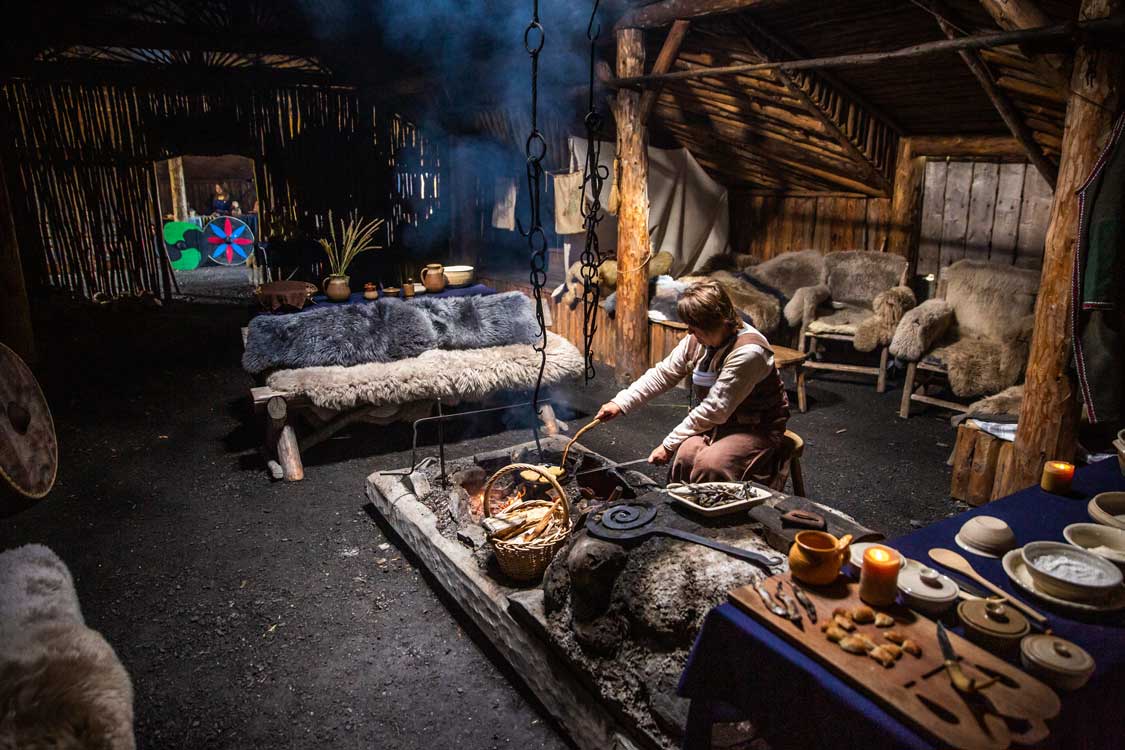 A woman works over a fire in a Viking settlement at Norstead Viking Village in Western Newfoundland