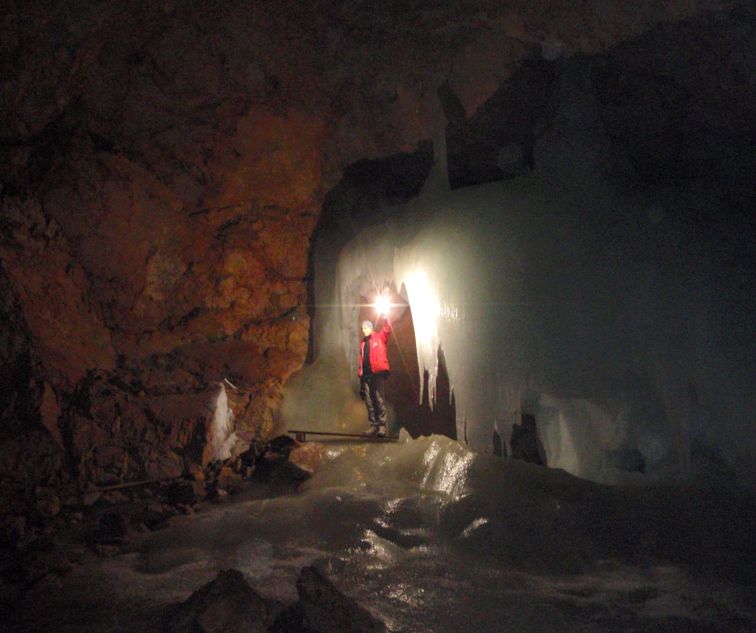 A guide holding a light shows up ice formations inside a cave - caves you can visit with kids