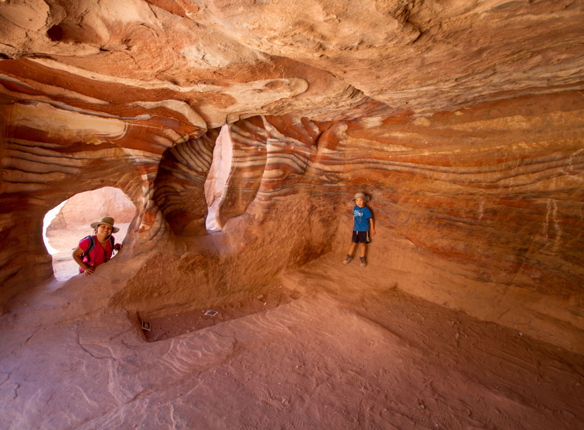 A young boy smiles inside a cave in Petra Jordan while his mother watches - caves you can visit with kids