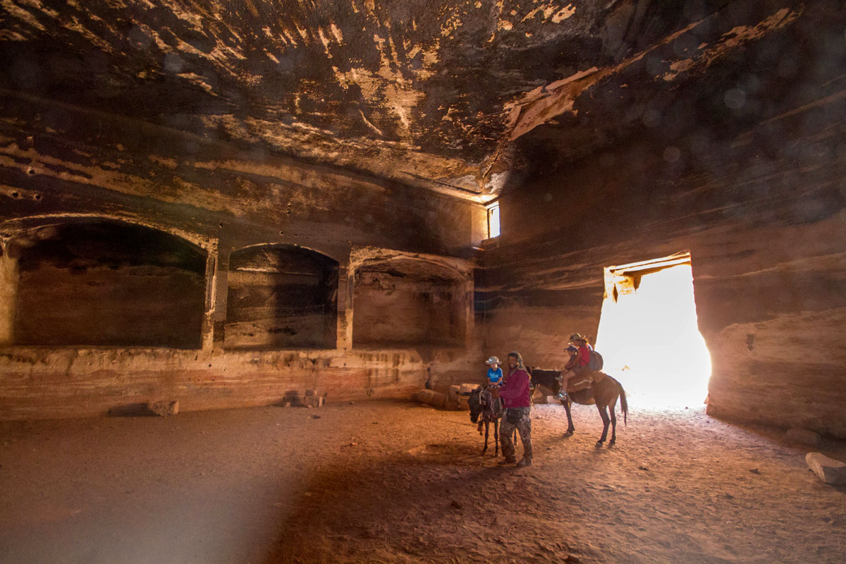 A guide and a young family ride horses inside a cave in Petra Jordan - Caves you can visit with kids