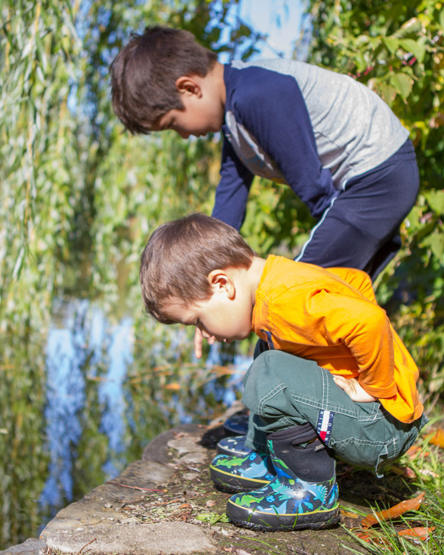 Two young boys check out a pond while wearing their bog boots - Bogs kids winter snow boots