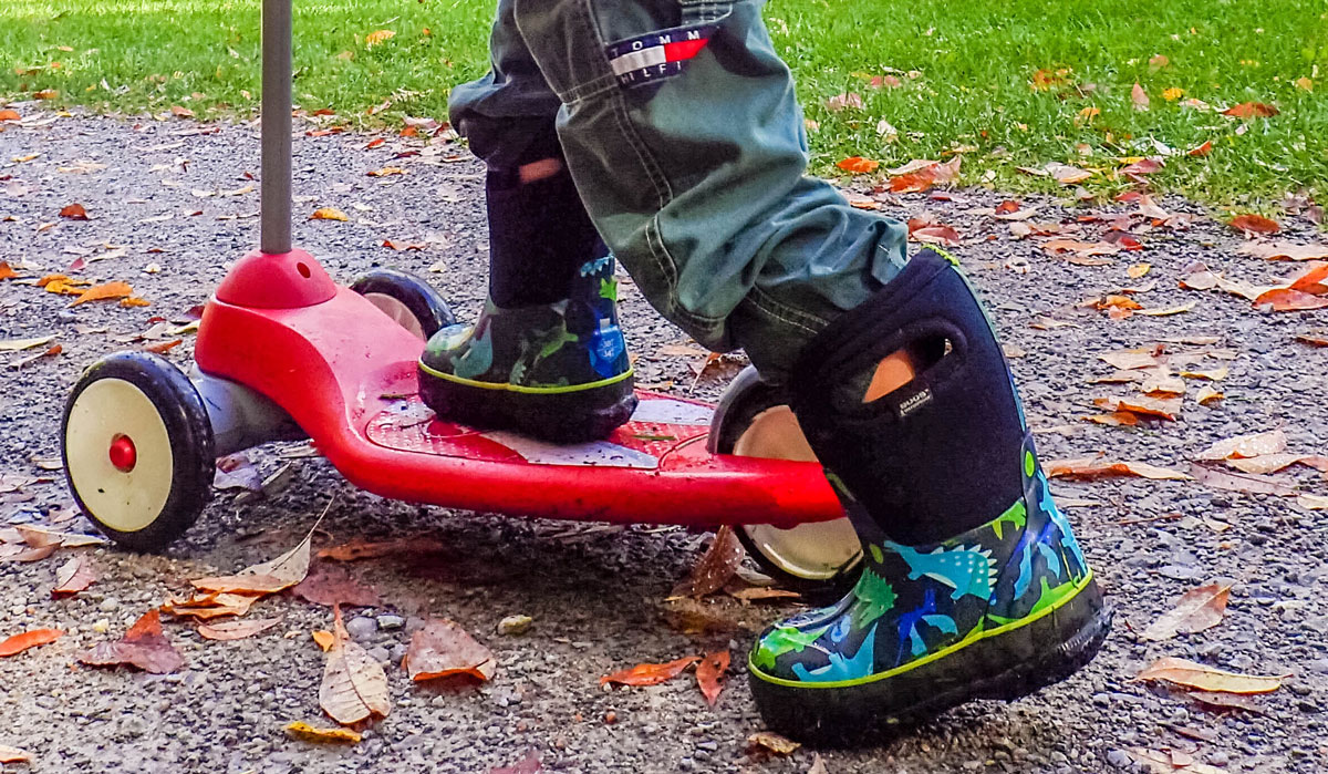 Close up of boots and scooter of a young boy - Bogs kids winter snow boots