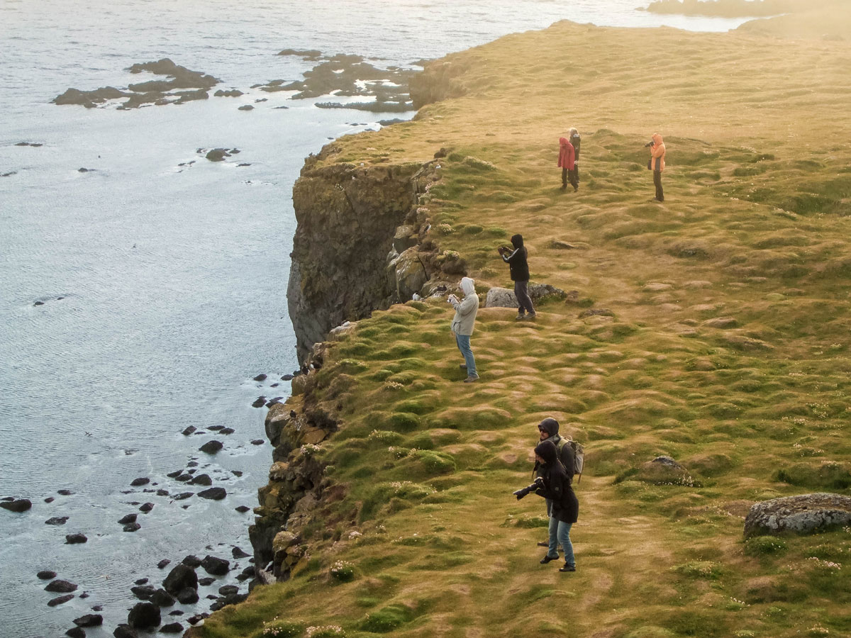 Photographers take in the sunset at the Latrabjarg Puffin Cliffs in Iceland