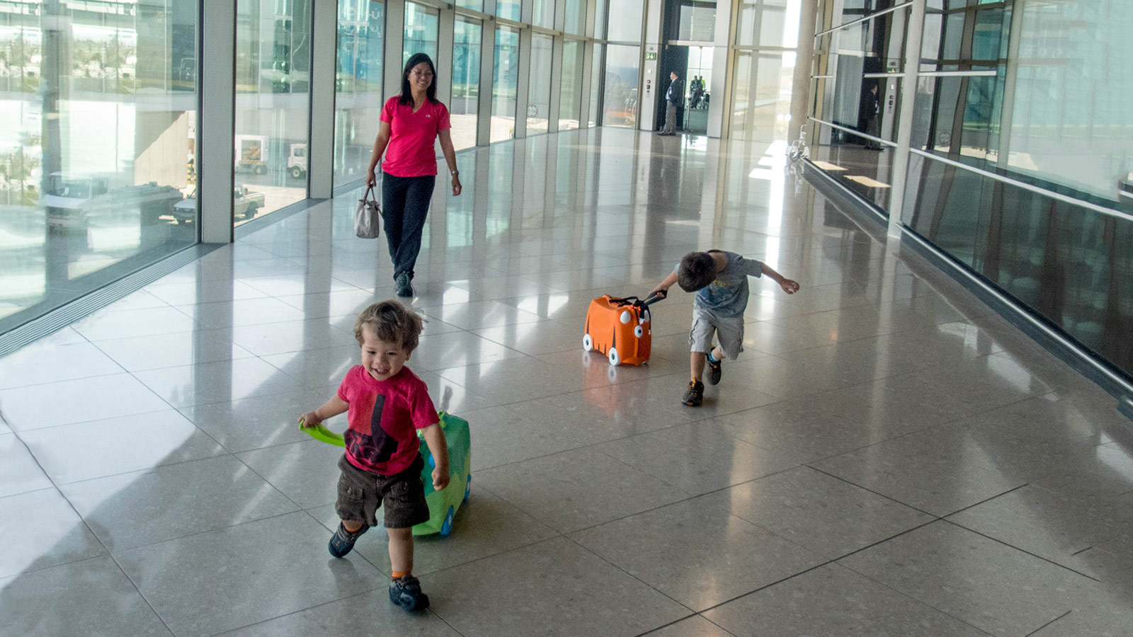 A woman and two young boys run through an airport