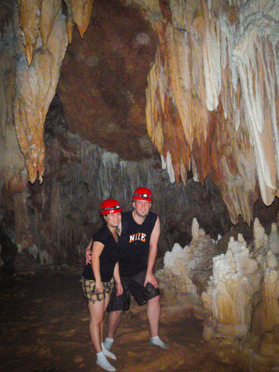 Man and woman pose in a cavern with stalactites and stalagmites in ATM cave in Belize.