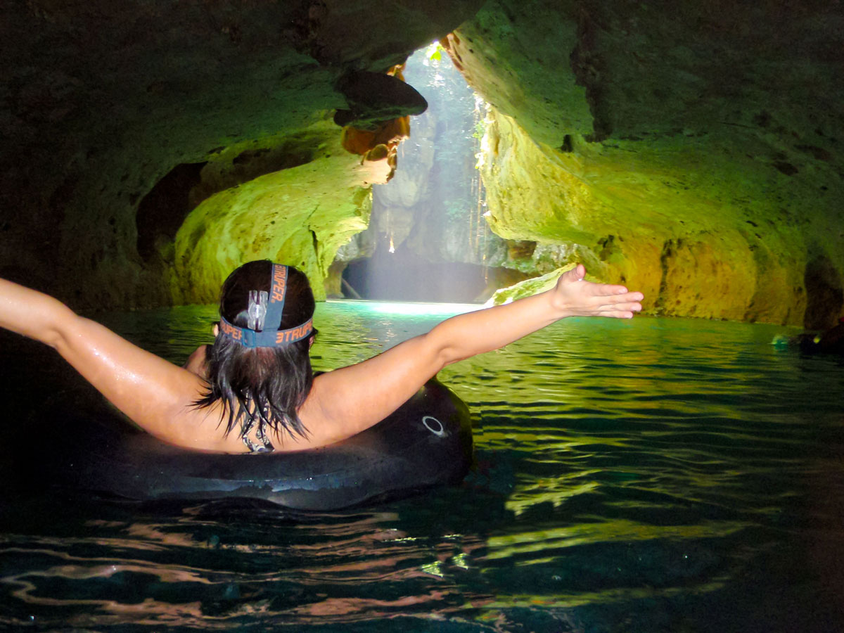 Woman cave tubing and heading towards the light.